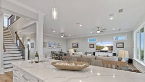 A spacious kitchen with a marble countertop, wooden bowl, and dining area with a view. - 🌊 Narrvelous – Sound-View 5BR Home w/ Pool, Tennis, Firepit & Walk to Beach (Navarre)