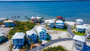A coastal residential area with beachfront properties, a pier, and a clear view of the ocean. - 🌊 Narrvelous – Sound-View 5BR Home w/ Pool, Tennis, Firepit & Walk to Beach (Navarre)