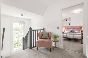 Una escalera que lleva a un dormitorio con una cama, una silla y una mesita con una planta.