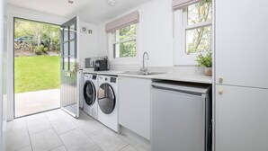A modern kitchen with a built-in washer and dryer, a sink, and a window with a view of the outdoors. - Captivating 4-bed House in Killin (Killin)