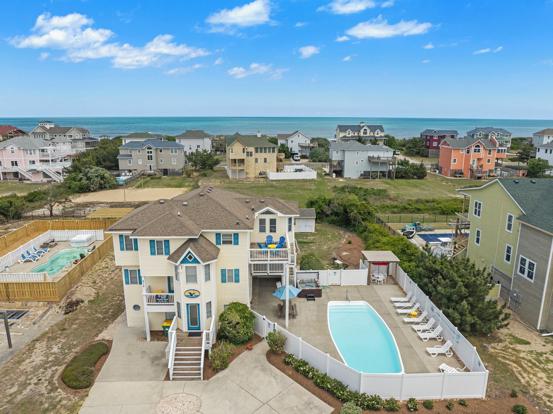 A residential area with houses, a swimming pool, and a view of the ocean.