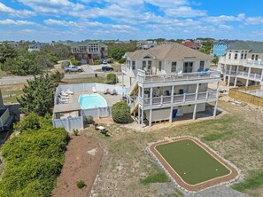 A multi-story residential building with a pool, a tennis court, and a fenced yard. - O'Shinn View: Short Walk to Beach | Pool, Hot Tub (Corolla)
