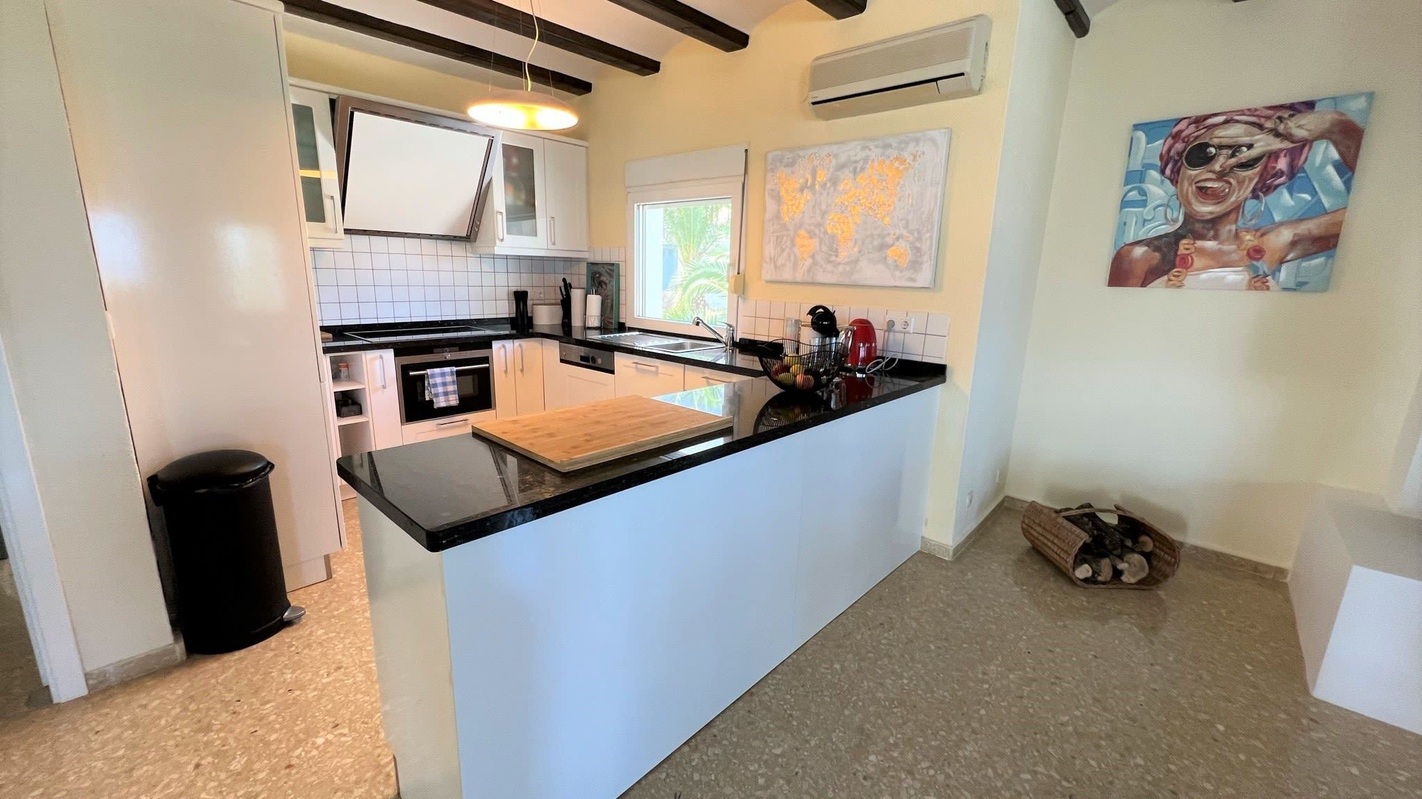 Une cuisine moderne avec des meubles blancs, un plan de travail noir et un îlot central en bois.