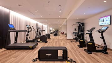 A modern gym with treadmills, elliptical machines, and a rowing machine.