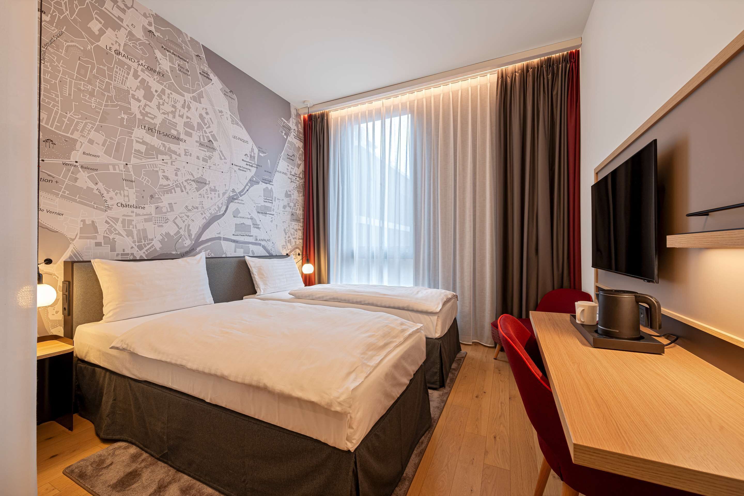 A hotel room with two beds, a map on the wall, a desk with a coffee maker, and a TV.