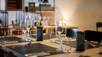 Una mesa de comedor dispuesta con vasos transparentes, cubiertos y un candelabro estampado.