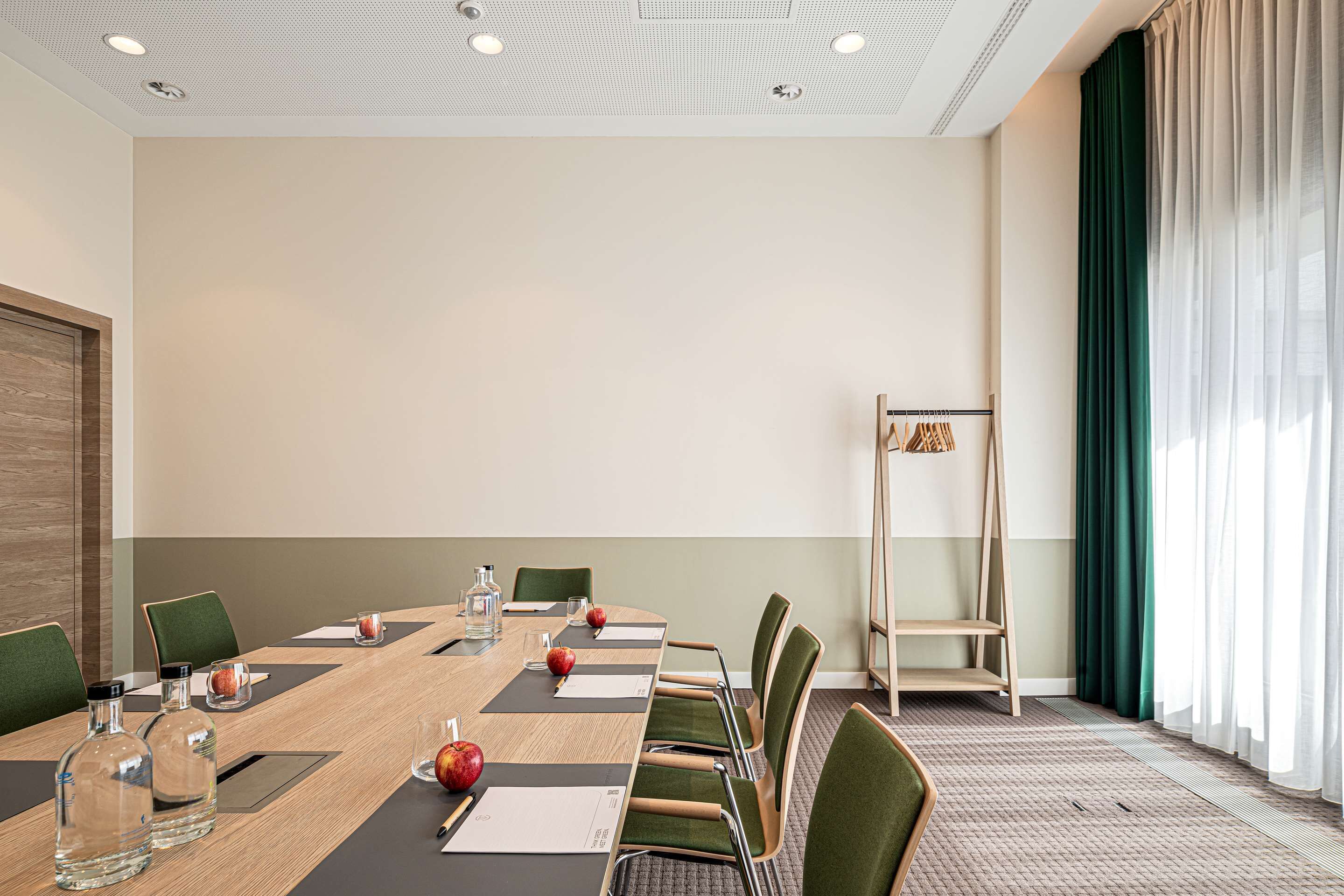 Uma sala de conferências com uma mesa comprida, cadeiras e uma estante escalonada.