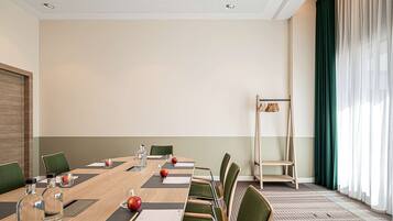 Uma sala de conferências com uma mesa comprida, cadeiras e uma estante escalonada.