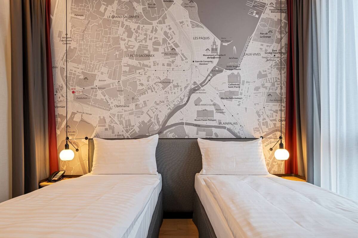 Une chambre d’hôtel avec deux lits, une carte accrochée au mur et un téléphone sur la table de chevet.