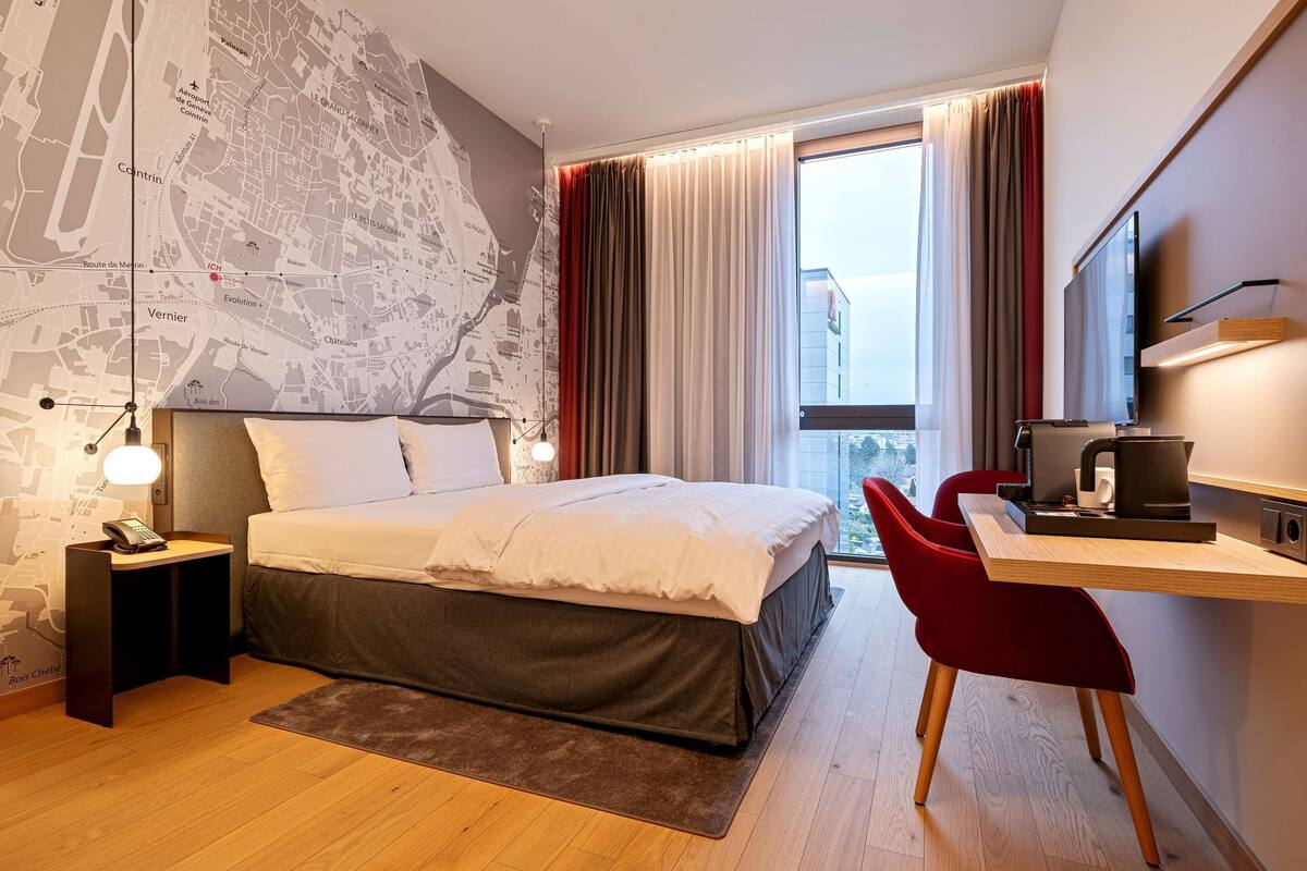 Une chambre d’hôtel moderne avec un grand lit, un bureau avec une chaise, un téléviseur à écran plat et une carte accrochée au mur.