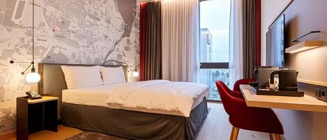 Ein modernes Hotelzimmer mit einem großen Bett, einem Schreibtisch mit Stuhl, einem Flachbildfernseher und einer Karte an der Wand.