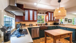 A modern kitchen with stainless steel appliances, a large window, and a hanging light fixture. - Heart of the River~Guerneville 5-Star~Easy Walk to River~HotTub~Dog~SummerFun (Guerneville)