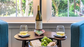 A table with a bottle of wine, two glasses, a heart-shaped plate with cheese and grapes, and a tray with crackers. - Heart of the River~Guerneville 5-Star~Easy Walk to River~HotTub~Dog~SummerFun (Guerneville)