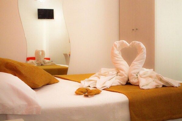 A hotel room with a bed, a heart-shaped towel arrangement, and a teddy bear on the bed. - Dependance Hotel Arte Mare  (San Vito Lo Capo)