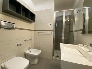 Une salle de bain équipée de toilettes, d’un bidet, d’une douche et d’un lavabo.