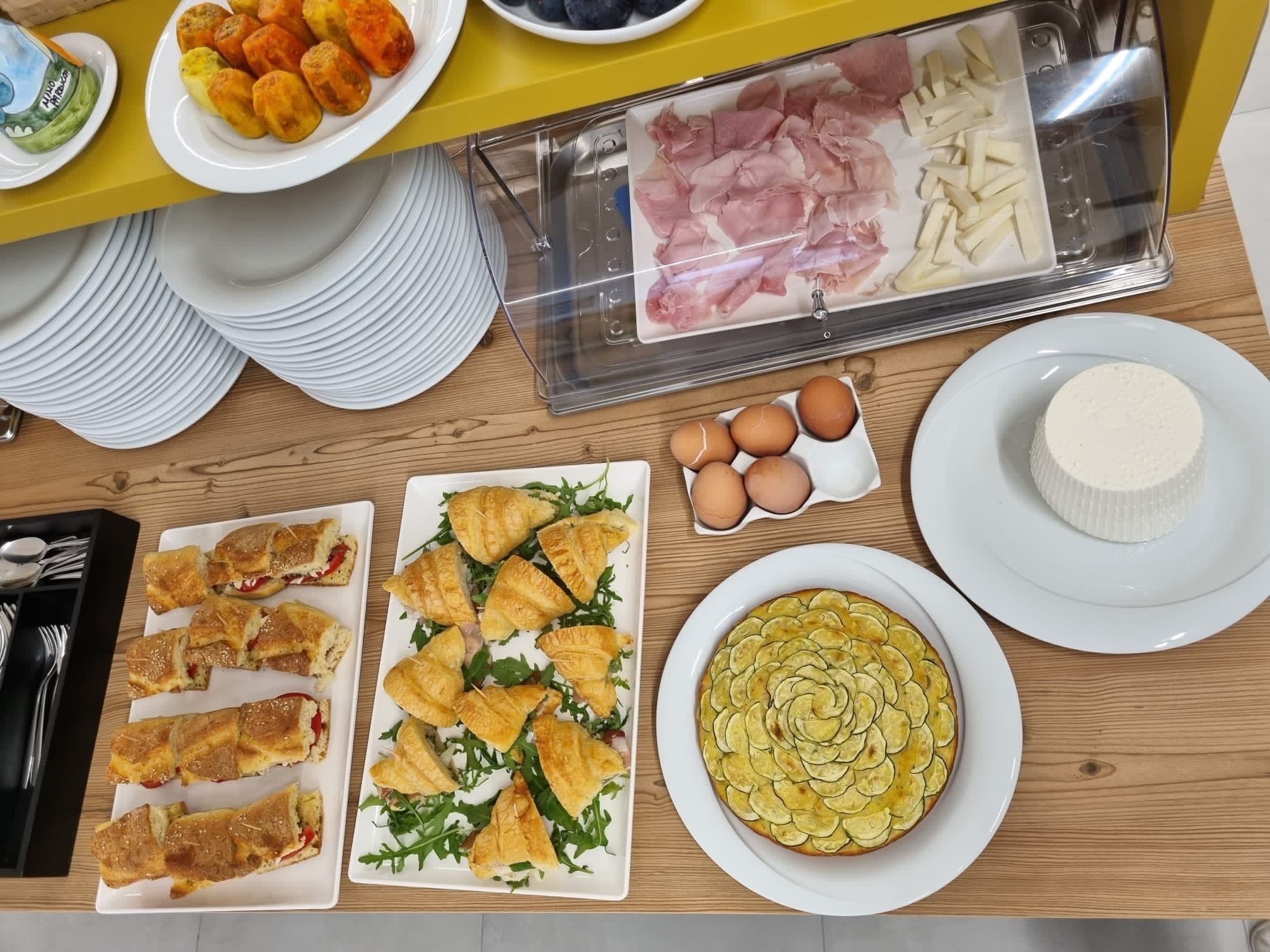A buffet table with various food items including pastries, meats, and a cheese dish.
