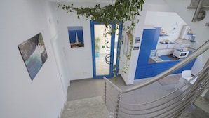 Una escalera con barandilla metálica que lleva a una habitación con pared azul, un lavabo y un microondas.