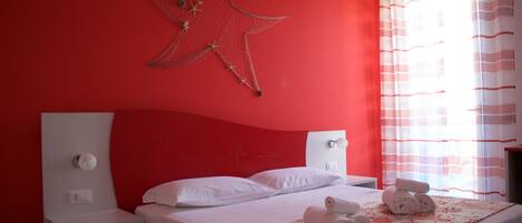 Un dormitorio con paredes rojas, una cama y un cabecero blanco, además de una decoración con motivos de estrellas.