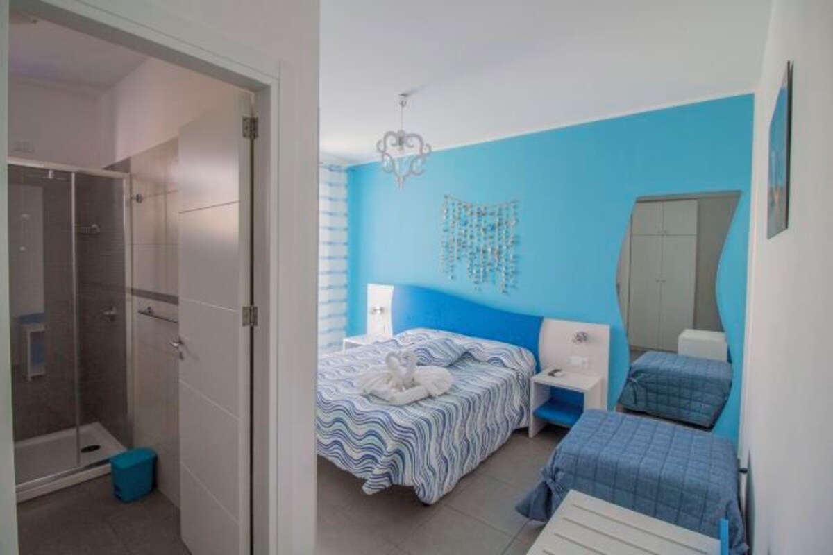 Una camera da letto con un letto, un comodino, uno specchio e uno spazio doccia.