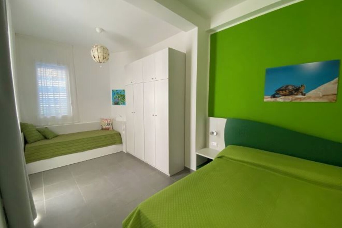 Una camera da letto con un letto, un armadio, una parete verde e un quadro.