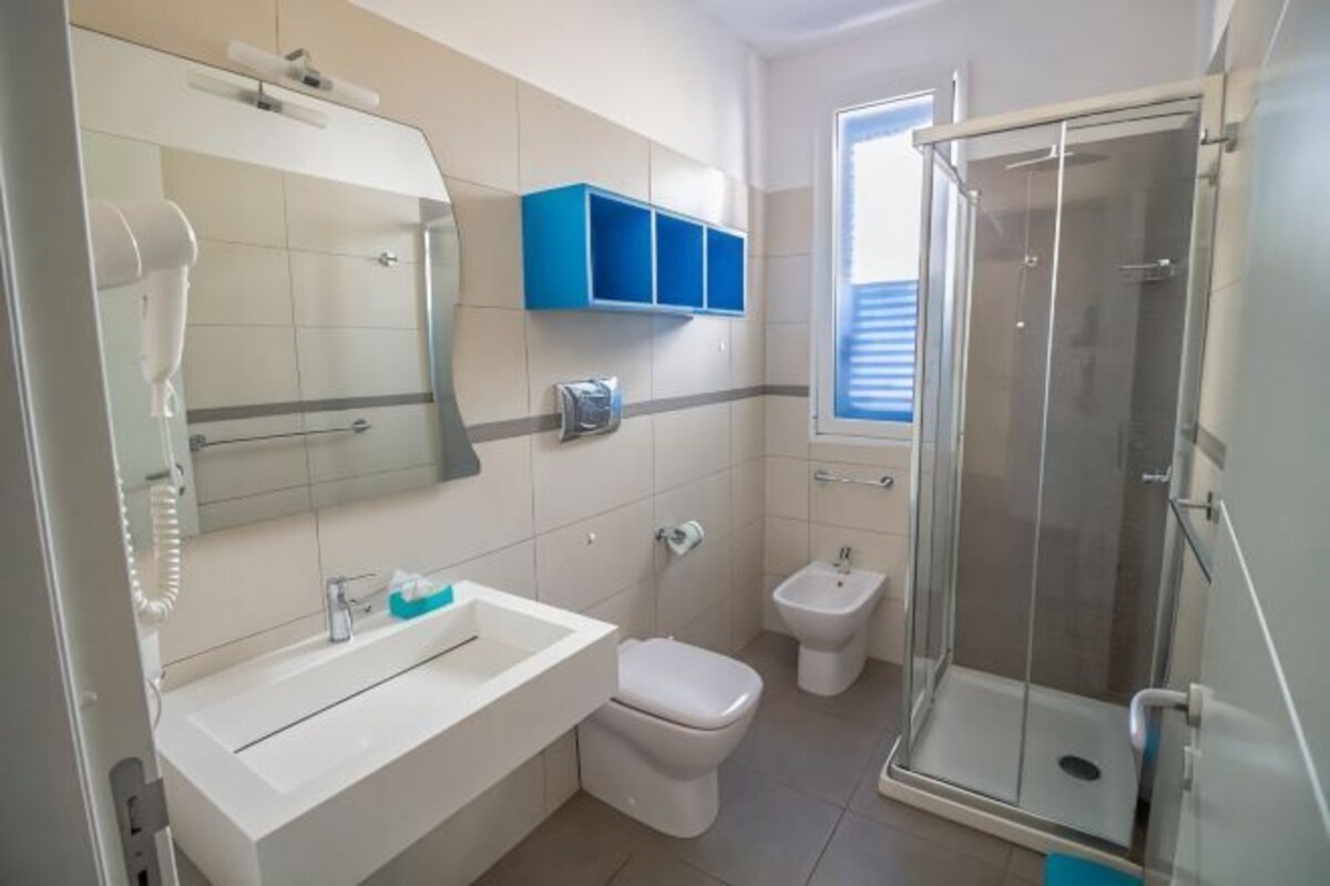 Un bagno con lavandino, WC, bidet e cabina doccia in vetro.