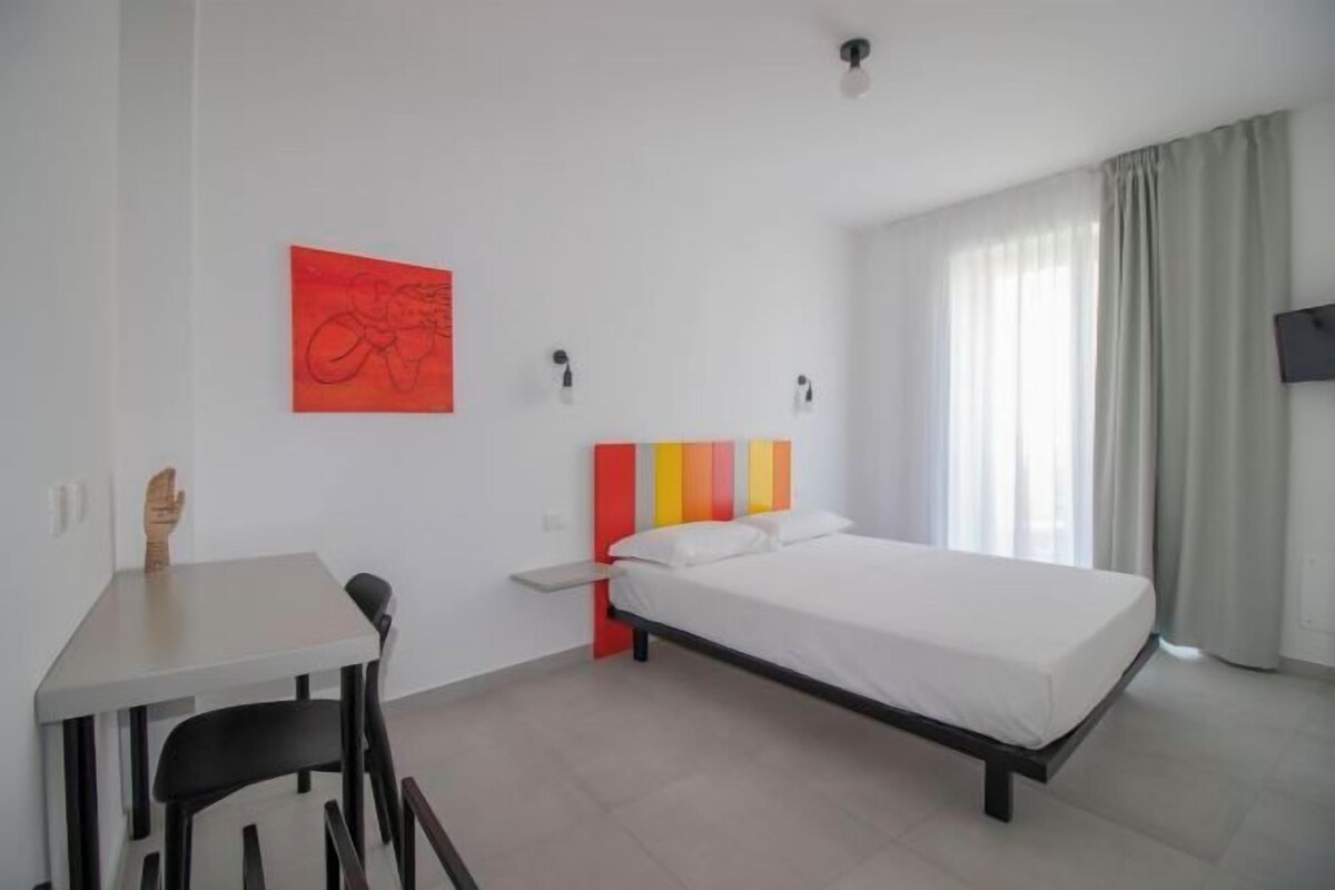 A hotel room with a bed, a desk, and a chair.