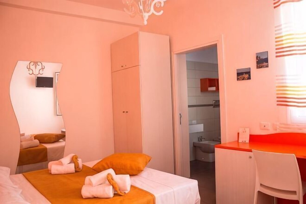 A bedroom with a bed, a desk, a wardrobe, and a mirror.