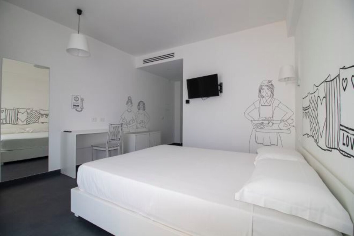 Una camera da letto con un letto grande, una scrivania, una sedia, una TV e un quadro appeso al muro.