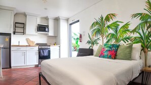 Una camera d'albergo compatta con un letto, angolo cottura e vista sull'esterno.