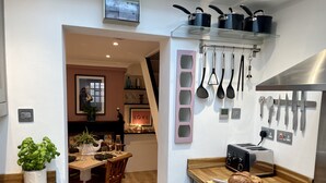 Een moderne keuken met een houten aanrecht, een gasfornuis en een broodrooster. Er is een eethoek met een tafel en stoelen, en een potplant.