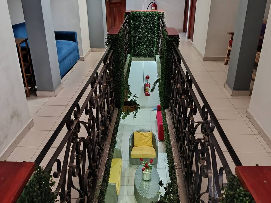 A corridor with a central walkway, flanked by seating areas and a fire extinguisher.