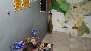 Un vestíbulo de hotel con un mapa del Caribe, un ventilador, una mesa con aperitivos y un florero.