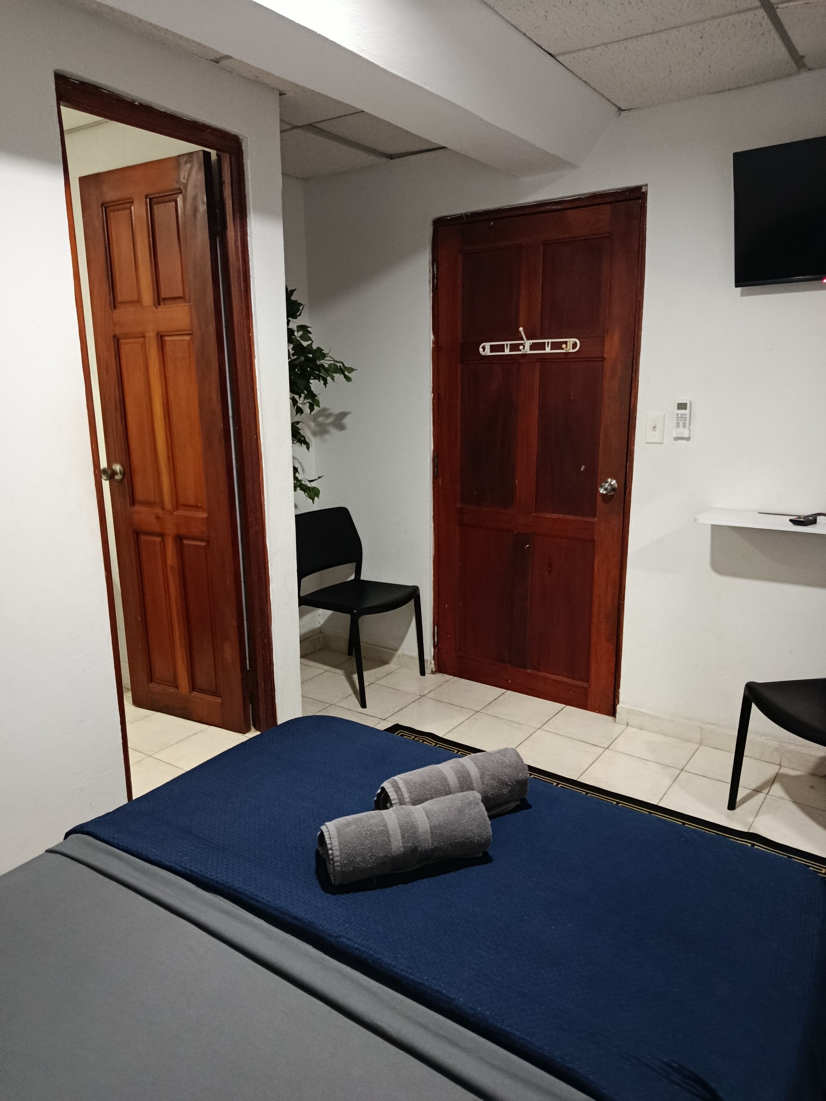 A room with a bed, a chair, a desk, and a television.