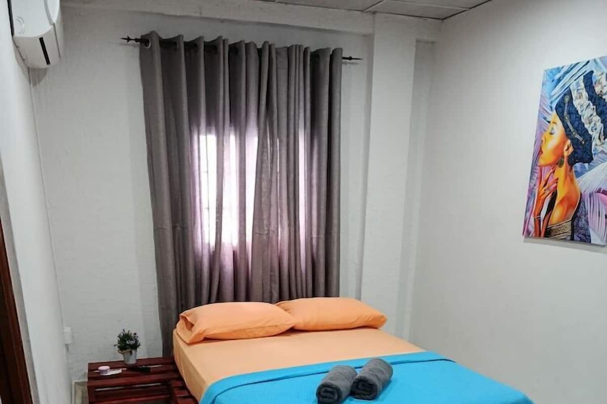 A small, neatly arranged bedroom with a bed, a desk, and a chair.