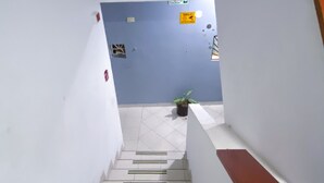 Una escalera con paredes blancas y una pared azul en la parte superior. Hay líneas de seguridad verdes y negras en los escalones.