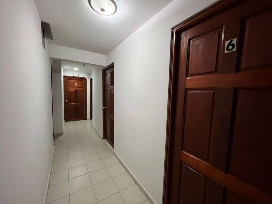 Un pasillo con suelo de baldosas, puertas de madera y una lámpara en el techo.