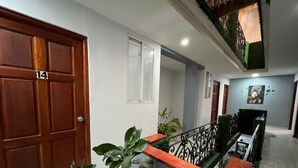 Un pasillo con una puerta de madera con el número 14, una ventana y una escalera con barandilla.