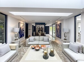 Un salon moderne comprenant un ensemble de canapés, une table basse agrémentée d’objets décoratifs et un lustre.