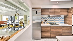Eine moderne Küche mit Holzausziehtüren, einem Edelstahlkühlschrank und einer gefliesten Spritzschutzwand.