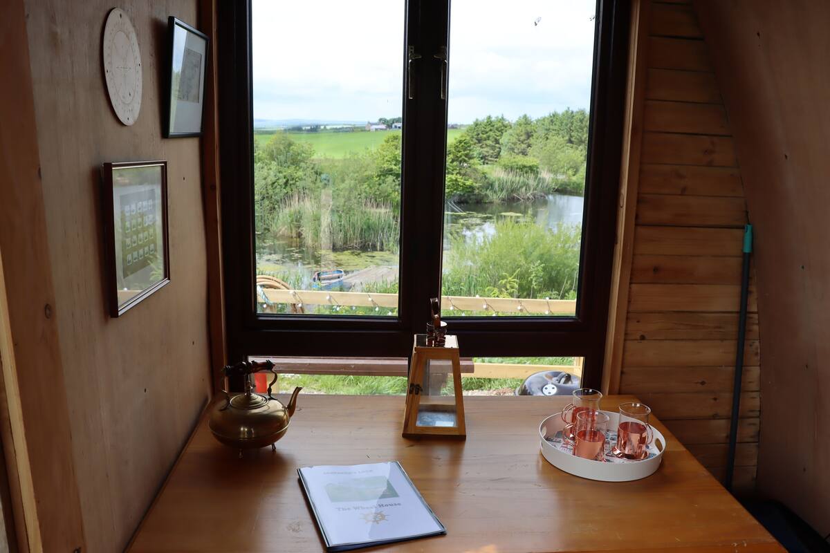 A wooden table with a book, a teapot, and a tray with cups and saucers.