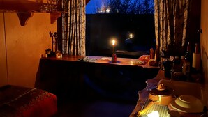 Una habitación acogedora con techo de madera, una mesa con una vela y vistas al exterior al atardecer.