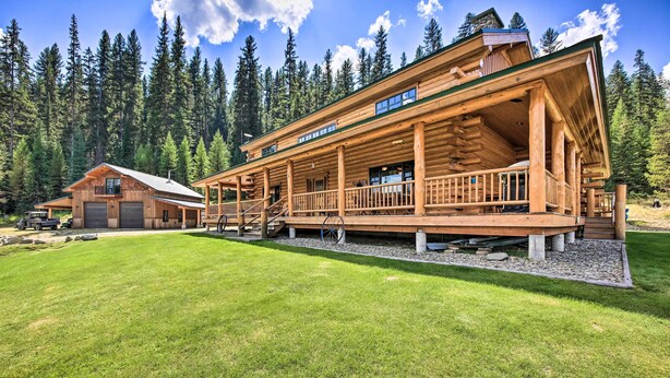 Eine große Blockhütte mit überdachter Veranda und einer separaten Garage.