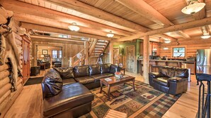 Ein Holzblockhaus-Interieur mit einem Ledersofa, einem Couchtisch und einem gemusterten Teppich.