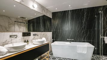Un baño moderno con una bañera independiente, dos lavamanos y un espejo grande.