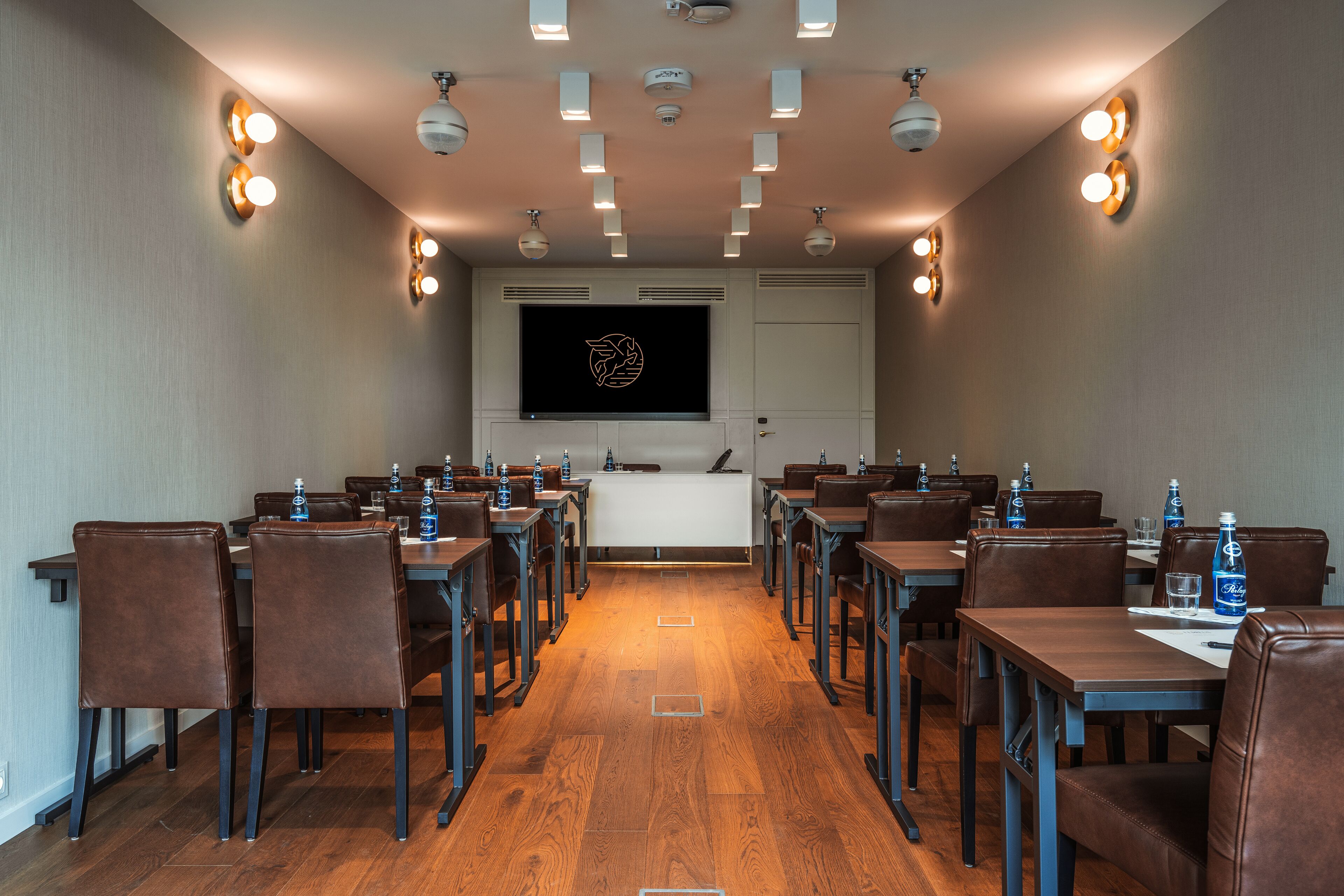 A conference room with a long table, chairs, and a screen at the front.