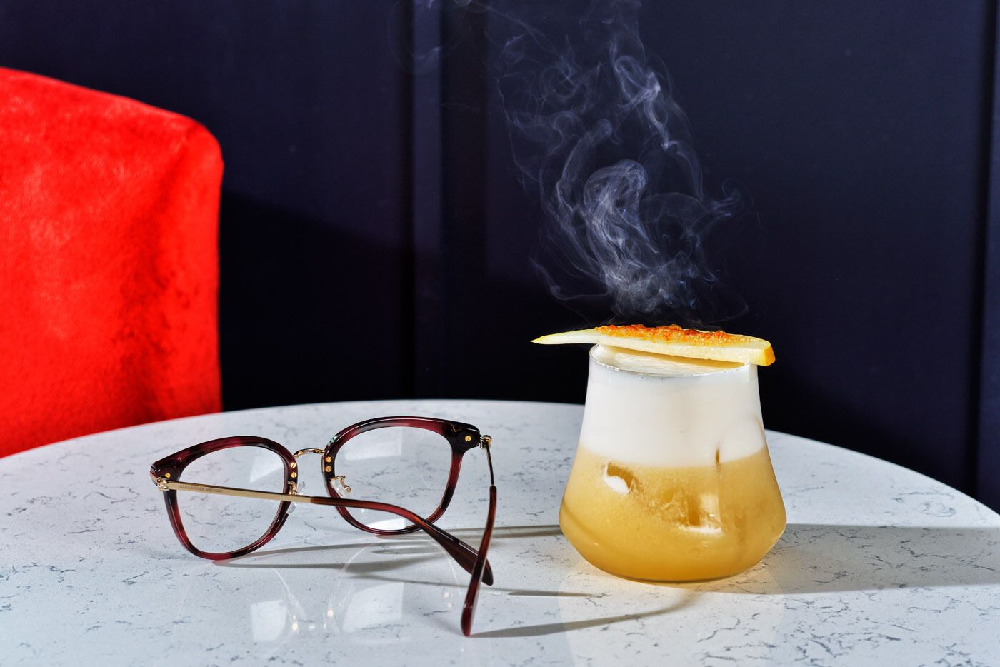 A martini glass with a lemon twist garnish on a marble table.