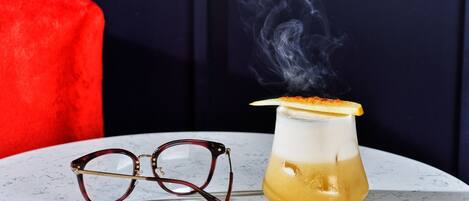 A martini glass with a lemon twist garnish on a marble table.