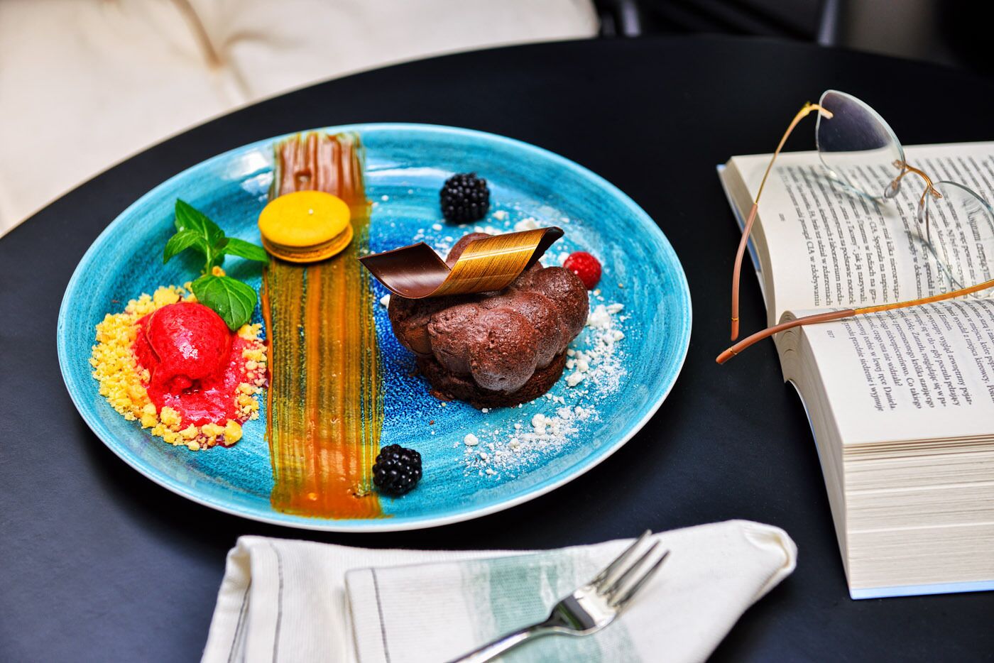 A dessert plate with various items on a table, accompanied by a book and a fork.