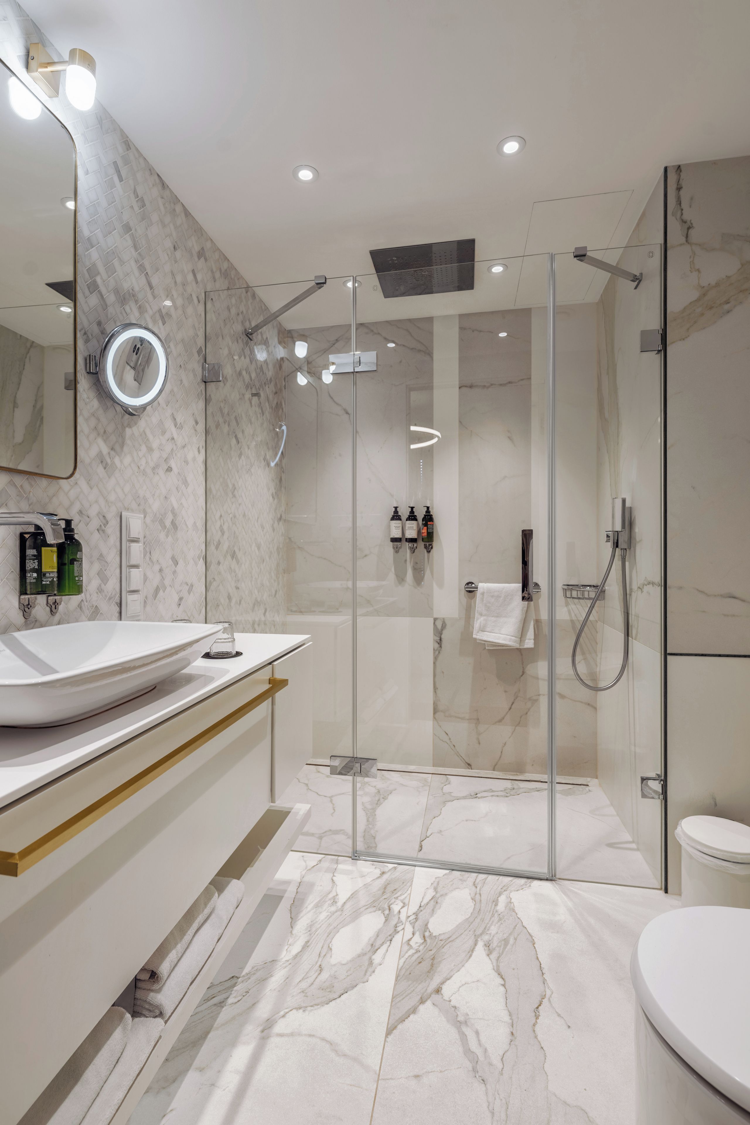 A modern bathroom with a glass-enclosed shower, a large mirror, and a vanity with two sinks.