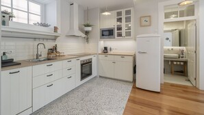 A modern kitchen with white cabinetry, a built-in microwave, and a stainless steel sink. - Chill Garden Apartment (Funchal)
